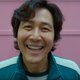 Gi-hun smiles for a photo in one of Squid Game's most famous scenes.